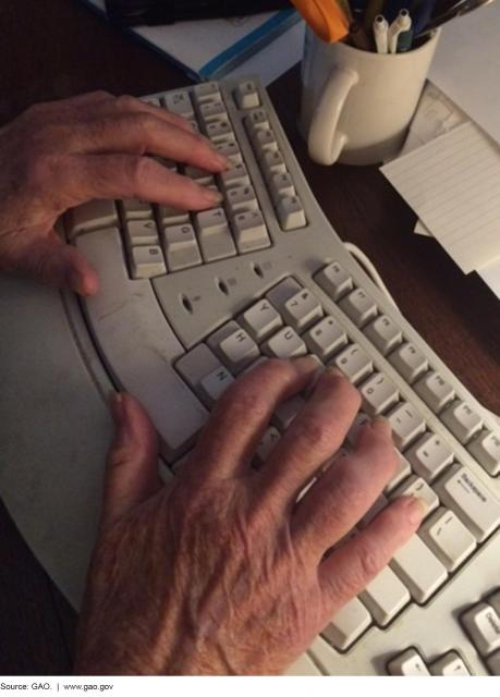 Photograph of an elderly person’s hands on a computer keyboard.