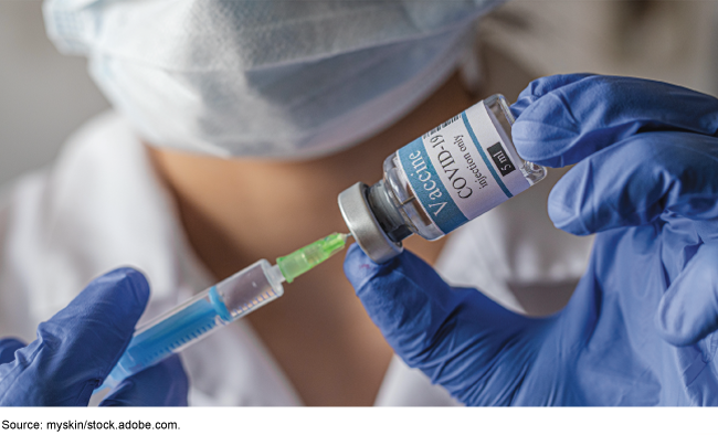 A medical person filling a syringe with a COVID-19 vaccine.