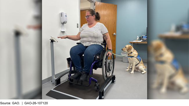 A woman in a wheelchair uses a wheelchair-accessible scale. Her service dog sits next to her.