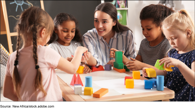 An adult woman at a table with young children playing with colorful blocks. An adult woman at a table with young children playing with colorful blocks.