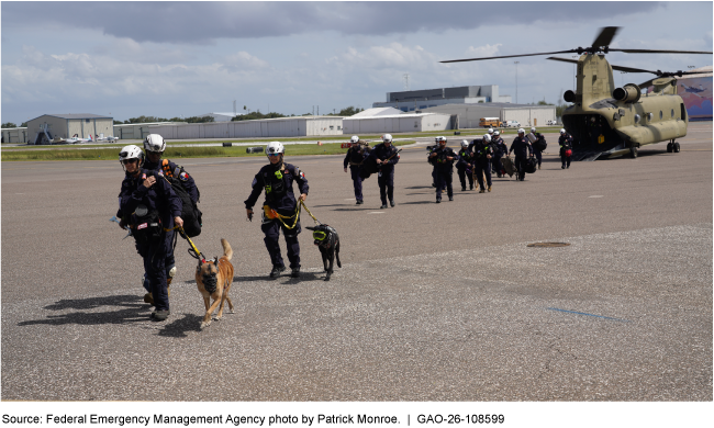 Several people wearing emergency responder equipment exiting a helicopter, some walking with dogs.