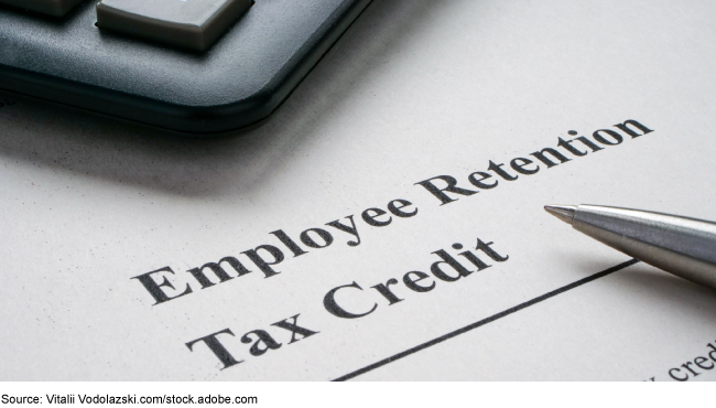 A calculator and pen lay on a paper with the writing 'Employee Retention Tax Credit.' A calculator and pen lay on a paper with the writing 'Employee Retention Tax Credit.'