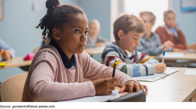 A young Black girl sitting in a classroom.