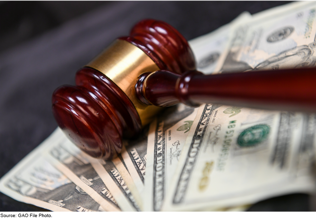 Stock image showing a close up of a judge's gavel sitting on a pile of money.