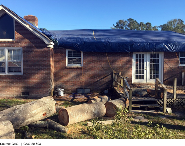 photo of a brick house with roof, deck, and tree damage