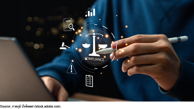 Businessperson using laptop with an image conceptualizing compliance.