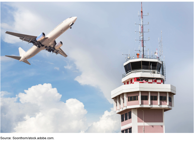 Air traffic control tower with airplane flying nearby