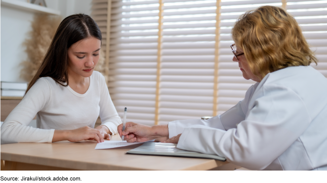 A teen and adult sitting at a table looking at a document