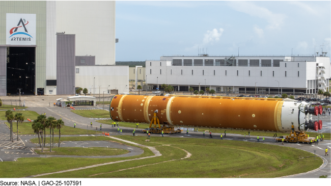 An Artemis rocket component with engines attached outside of a NASA facility