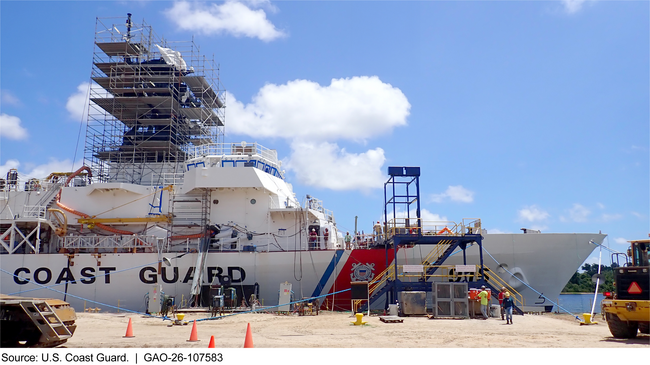 U.S. Coast Guard ship beside a dock with construction scaffolding and equipment on it.