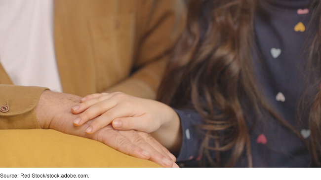 close up of the hand of a child resting on the hand of an older adult