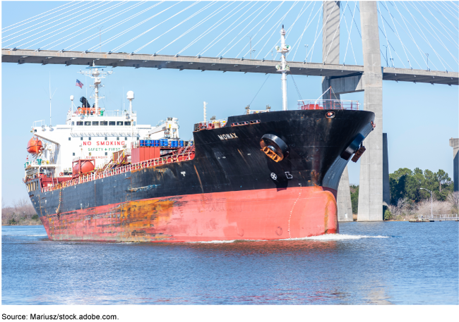 image of cargo ship under a bridge