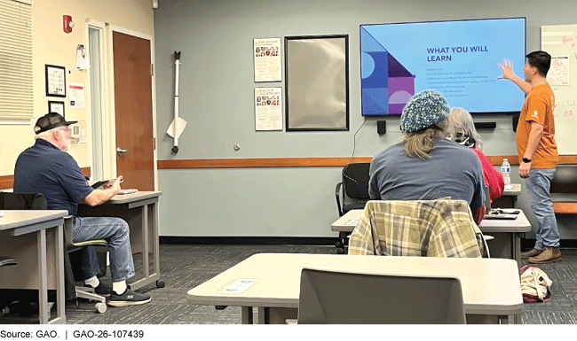 A classroom setting with older adults sitting at desks and a person pointing to a T.V. screen that says &What you will learn.