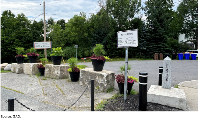 A row of flowerpots atop concrete blocks alongside a small stone obelisk marker that says United States A row of flowerpots atop concrete blocks alongside a small stone obelisk marker that says United States