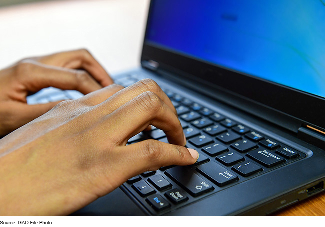 Hands typing on a laptop keyboard.