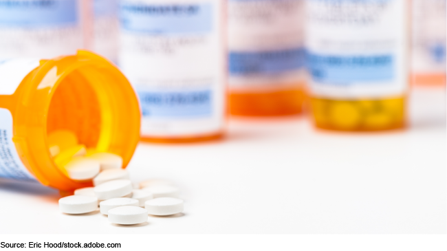 An orange medicine bottle with tablets spilling out