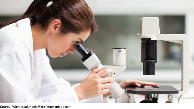 A scientist looking through a microscope.