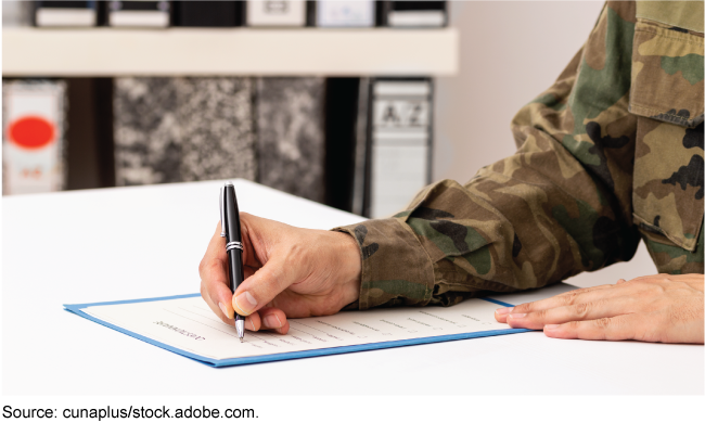 A person in a military uniform fills out a form.