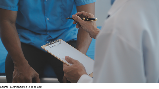 A doctor holding a clipboard with a man on an examination table