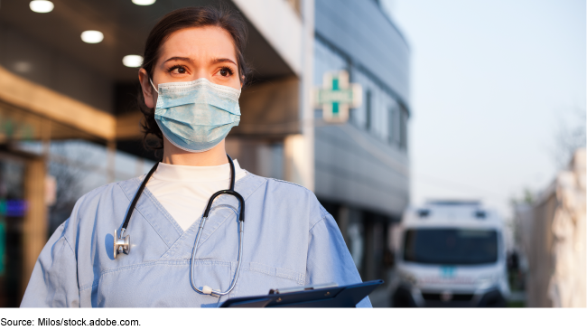 Woman wearing a face mask and medical scrubs, with a stethoscope around her neck.