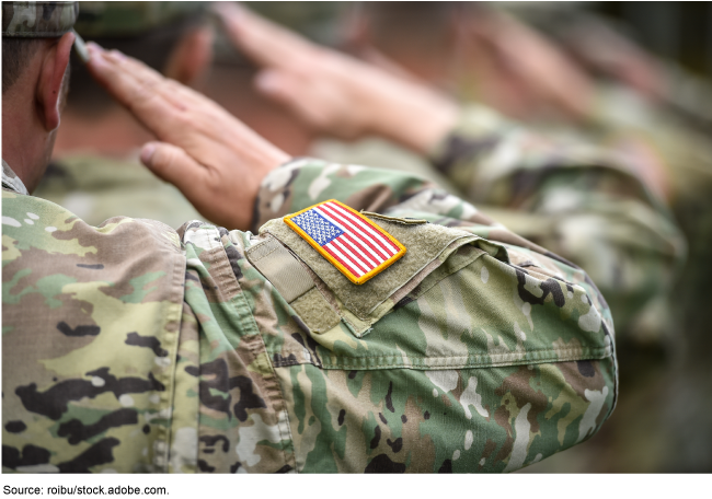 Person in a U.S. military uniform saluting with their hand.