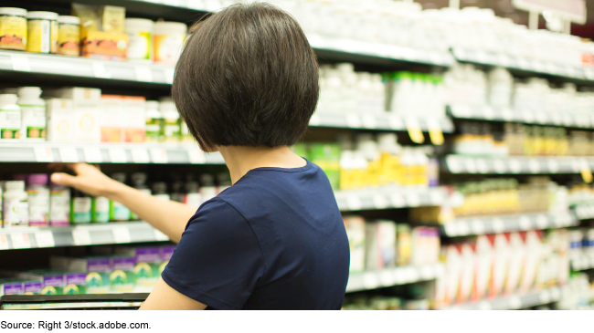 A person looking at shelves of over-the-courter drugs at a drug store. 