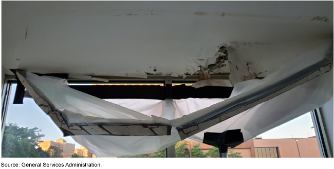 A ceiling in a room with visible water damage with plastic wrap below it to catch falling debris.