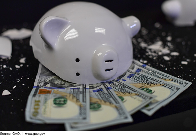 Five $100 bills are on a table beside a broken piggy bank.