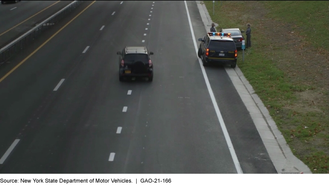 A car exits the right lane to provide ample space to a first responder parked on the shoulder.
