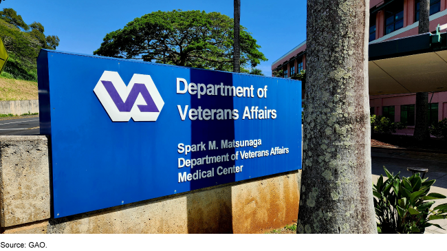 The exterior of a VA building in the background and VA sign in the foreground 