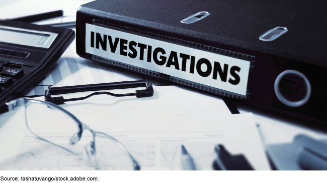 A binder that says investigations on a desk with office supplies and documents. A binder that says investigations on a desk with office supplies and documents.