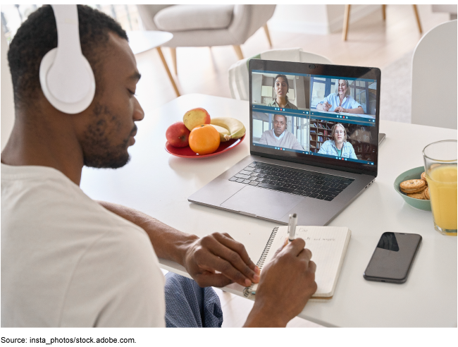 A person taking notes while on a video meeting.