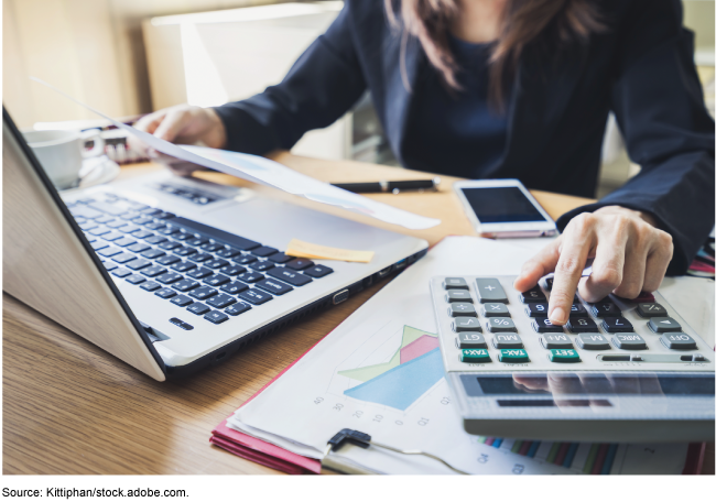 Person working at a desk with a laptop and calculator Person working at a desk with a laptop and calculator
