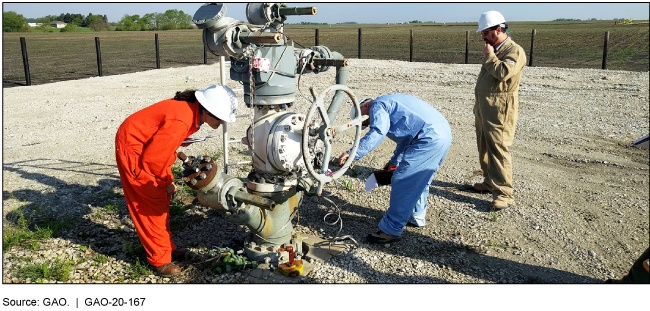 People in coveralls and hardhats examining infrastructure