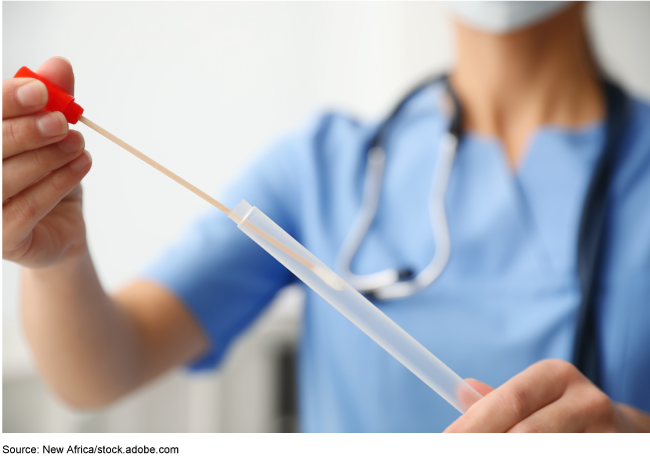 person wearing medical scrubs holding a swab inserted into a tube