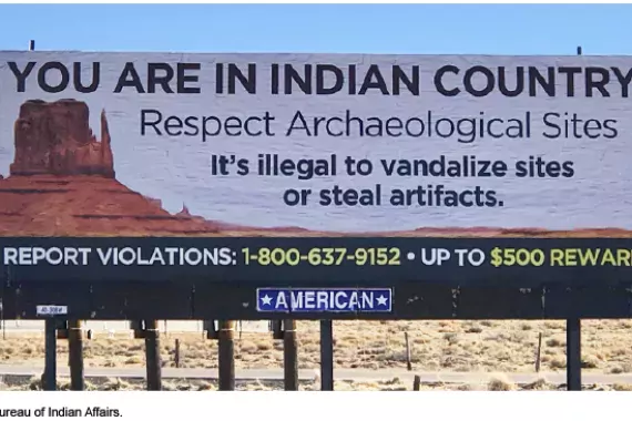 A billboard in a desert environment reads &quot;You are in Indian Country. Respect Archaeological Sites. It's illegal to vandalize or steal artifacts. Report Violations, Up to $500 Reward.