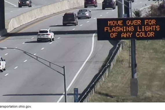 Photo showing an electronic sign on the side of an interstate or highway that reads in orange &quot;MOVE OVER FOR FLASHING LIGHTS OF ANY COLOR.&quot;