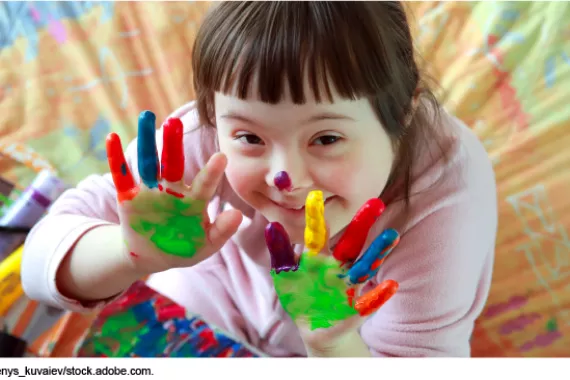 Photo showing a young child playing with finger paints.