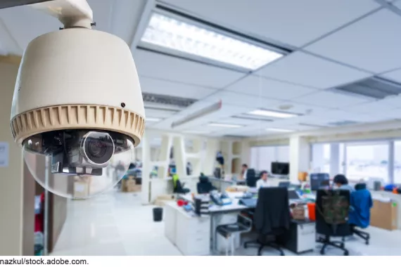 Stock image showing a camera mounted near the ceiling in an office space.