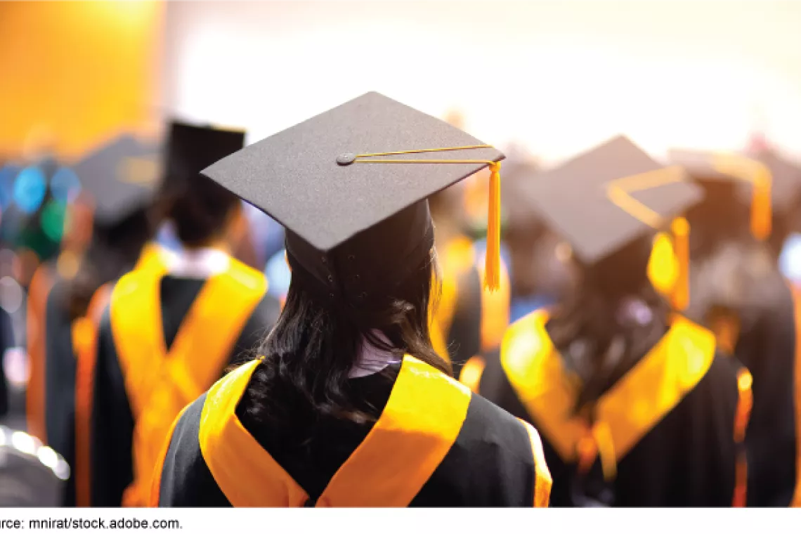 Stock image showing college graduates in cap and gown with gold sashes.